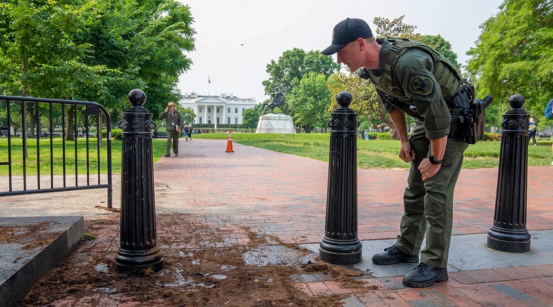 Un oficial inspecciona una barrera de seguridad cerca de la Casa Blanca en busca de daños, el 23 de mayo de 2023. (Alex Brandon / AP)