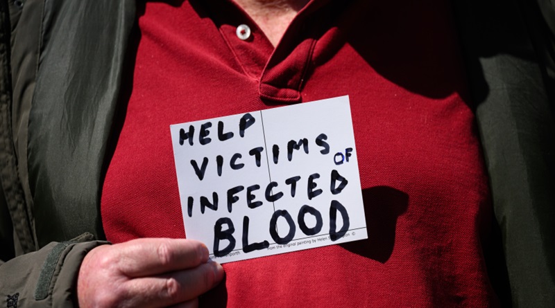 Un familiar de uno de los pacientes infectados sostiene un cartel que reza “Ayuda a las víctimas de sangre infectada”, este lunes en Londres (Leon Neal / Getty/Efe)
